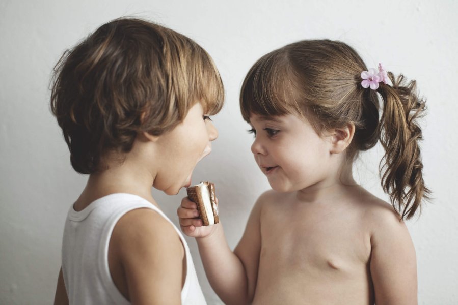 Small girl give an ice cream to a small boy