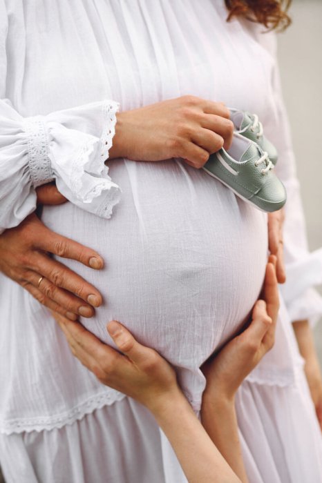 pregnant-woman-holding-green-baby-slippers-near-pregnant-belly-family-concept