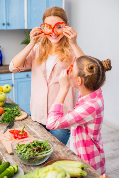 smiling-mother-daughter-looking-through-slice-red-bell-pepper-kitchen smiling-mother-daughter-looking-through-slice-red-bell-pepper-kitchen
