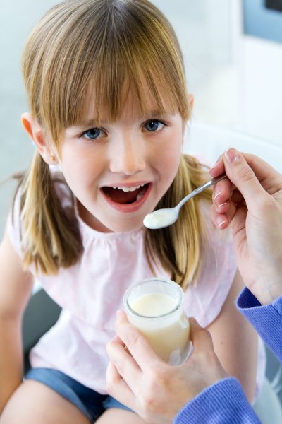 young-woman-little-girl-eating-yogurt-kitchen
